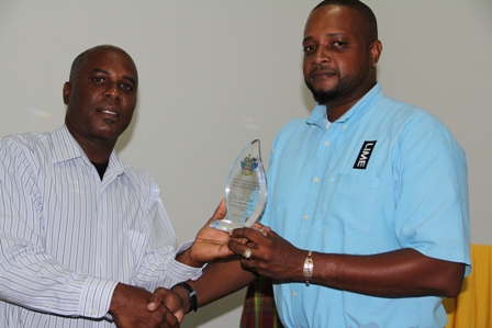 Permanent Secretary in the Ministry of Youth and Sports Mr. Alsted Pemberton presents award to Lester Liburd for his contribution to Culture